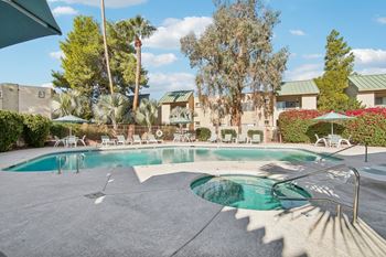 A large outdoor swimming pool surrounded by trees and lounge chairs.